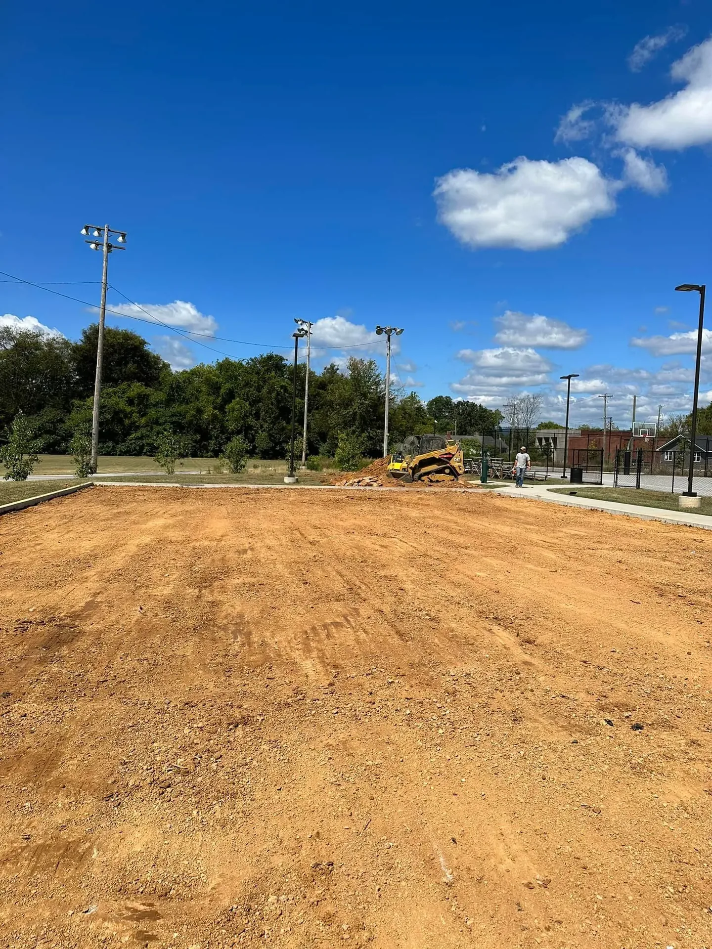Freshly graded and compacted dirt pad for a new parking area at a community park