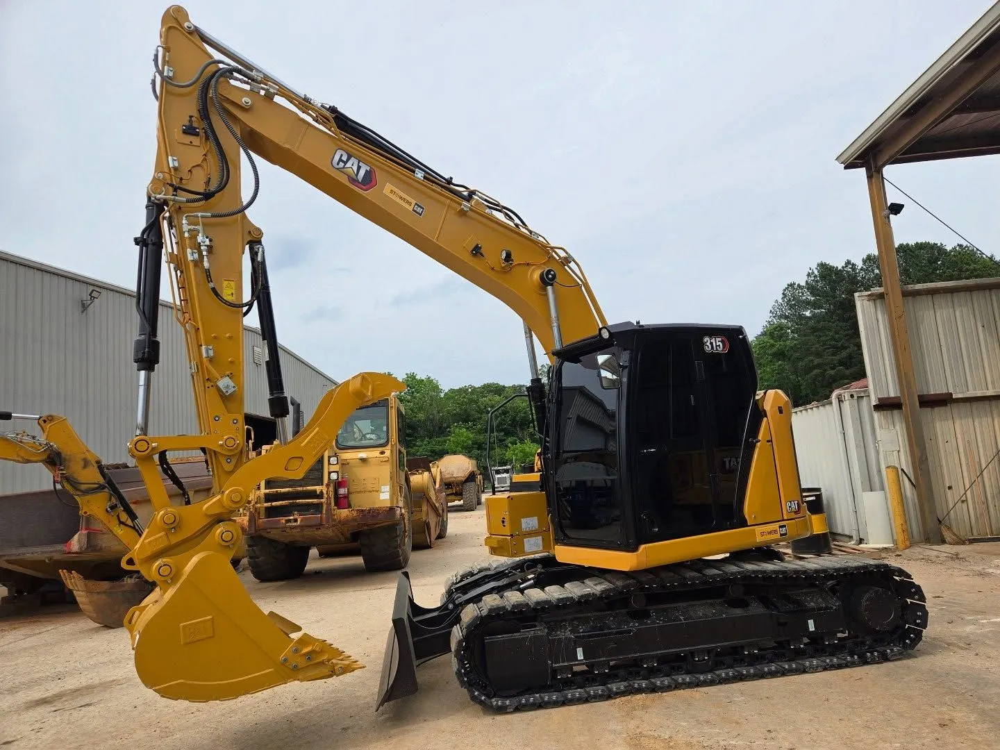 Yellow Caterpillar excavator with black cab on tracks, parked outdoors.
