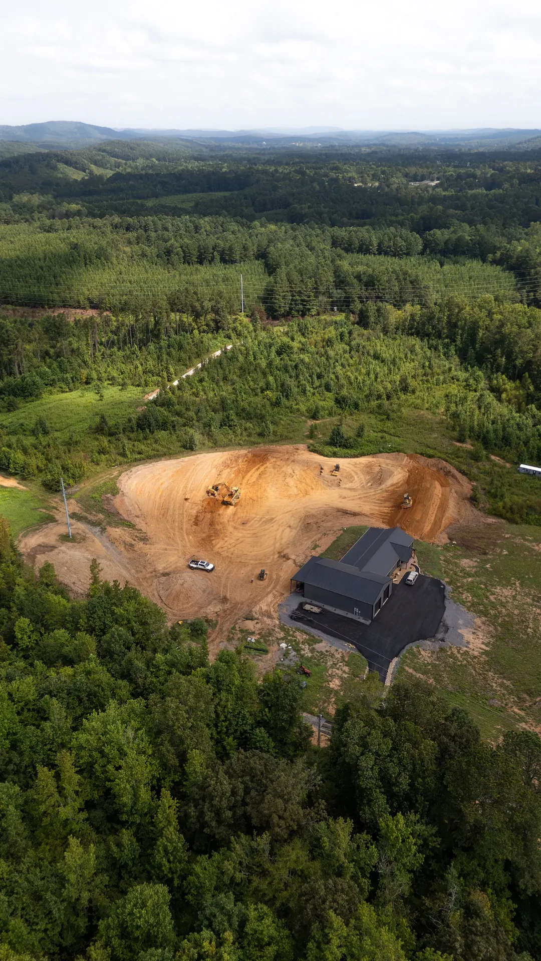 Aerial view of a house surrounded by a cleared area in a forest.