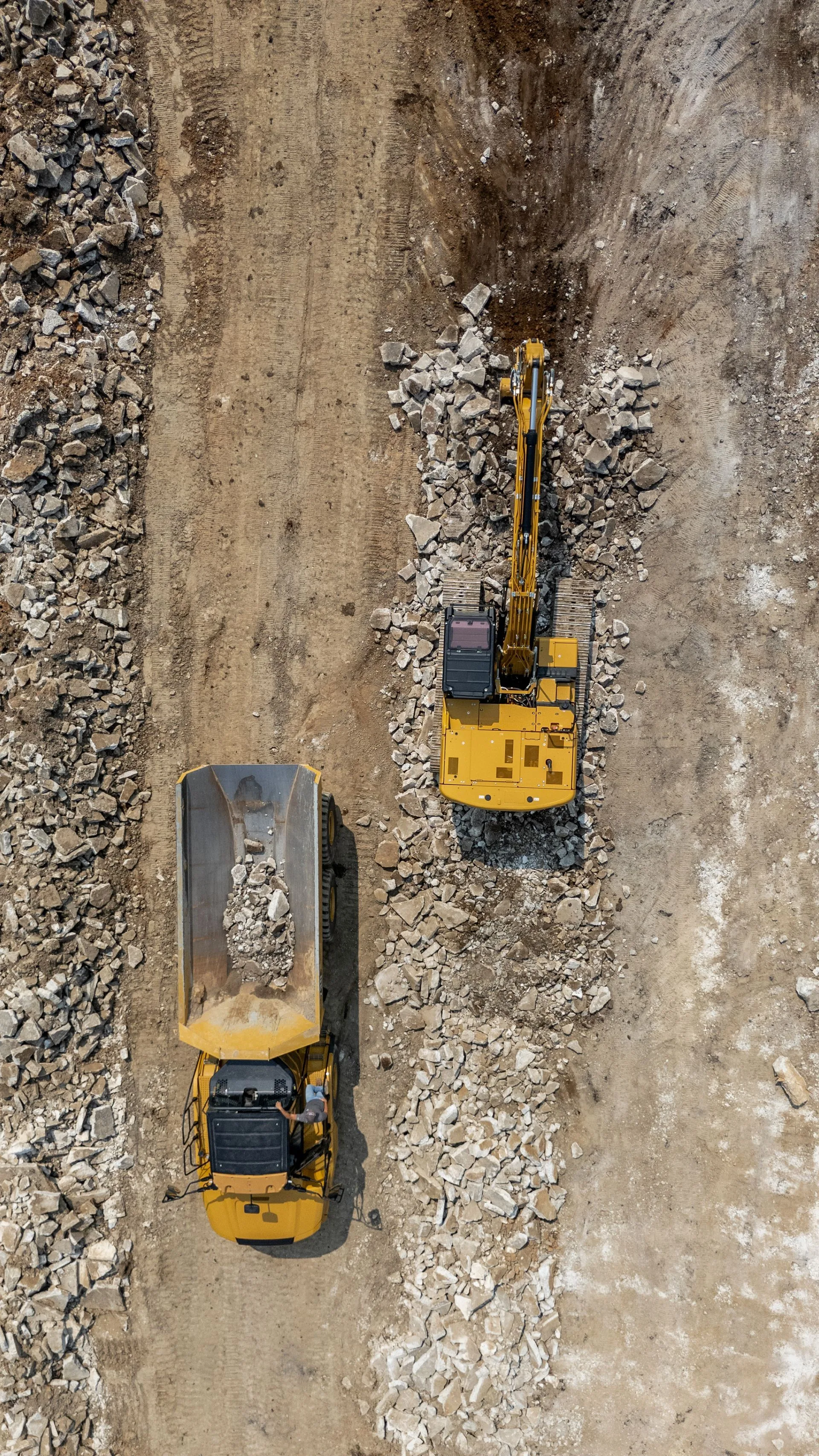 Yellow excavator loading a dump truck with debris in a construction site.