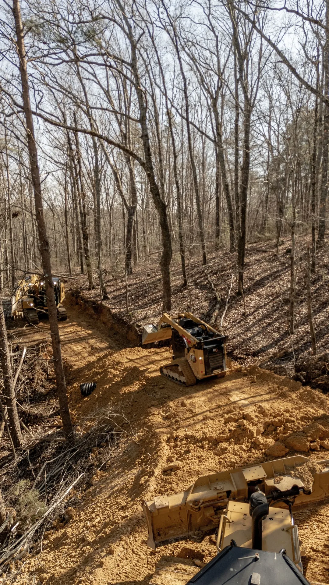 Construction site in a forest with heavy machinery clearing land.