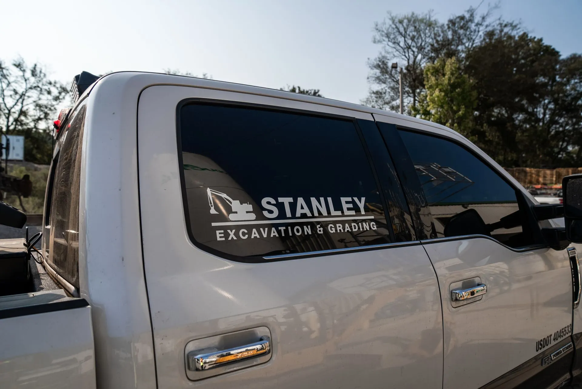 White truck with Stanley Excavation & Grading logo on the window.